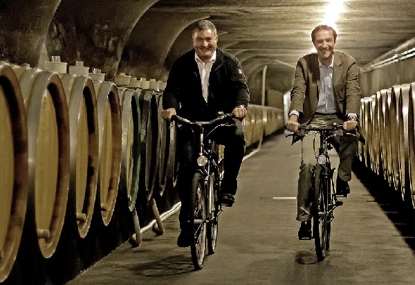 Das Foto zeigt Dr. Kartsen Weyand und Johannes Becker bei einer Radtour im Keller der Bischöflichen Weingüter Trier.